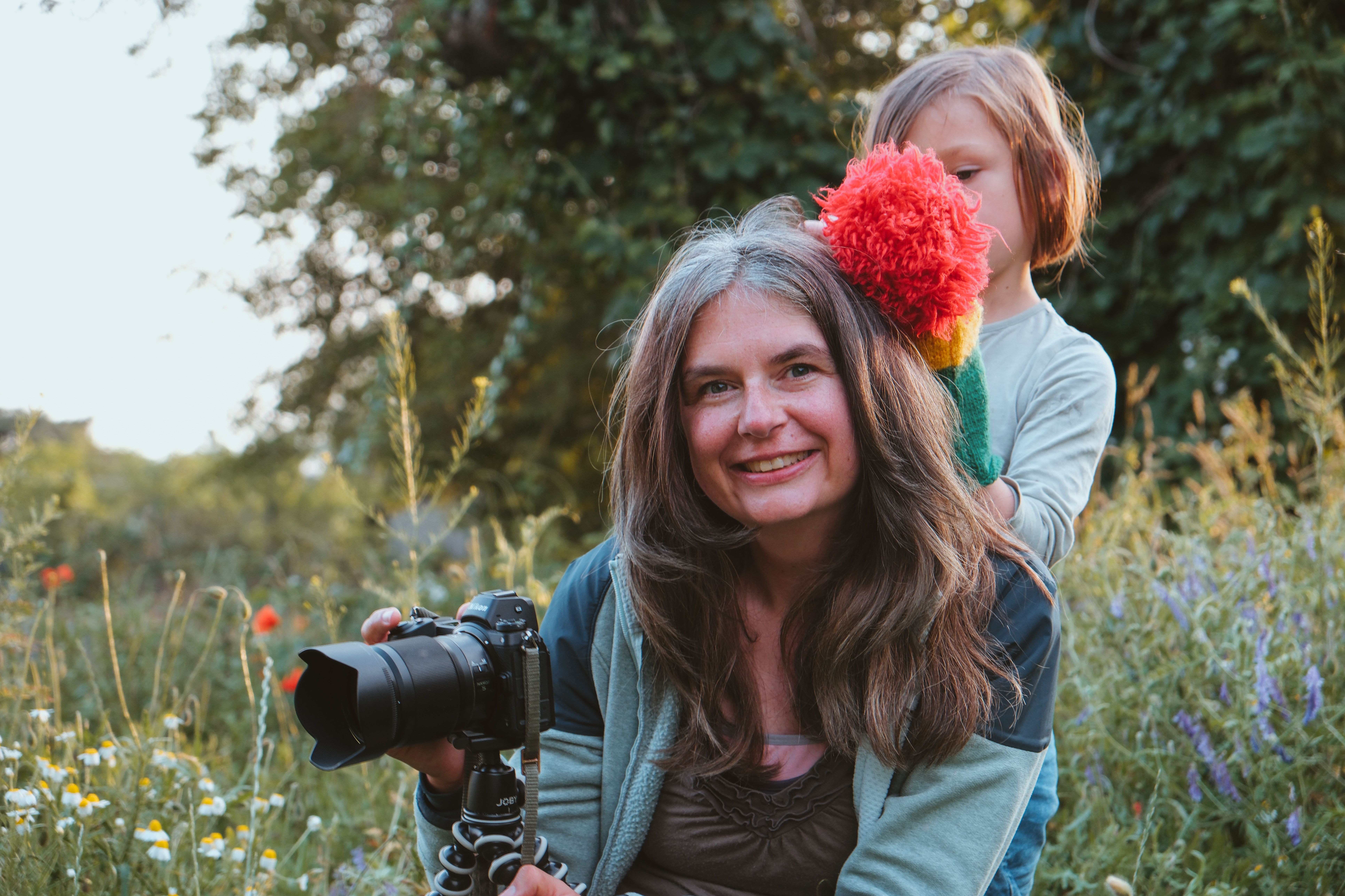 Mareen Zimmermann mit Kamera und ihrer Tochter auf einer Wildblumenwiese – Vereinbarkeit von Familie und Business