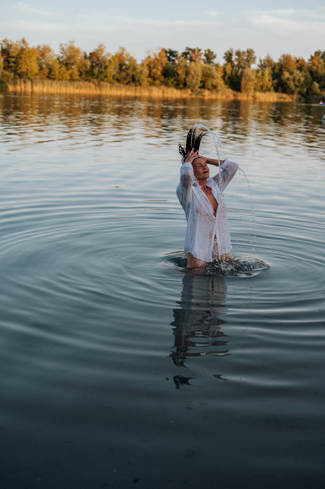 Frau schleudert nasse Haare im See, weißes Hemd, Abendlicht – befreiendes Moment in der Seelenfotografie von MALEA Fotografie
