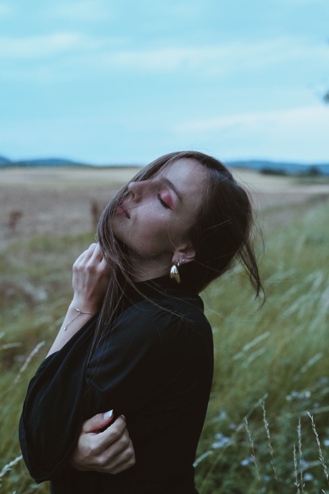 Frau mit geschlossenen Augen und vom Wind bewegten Haaren auf einem Feld im Abendlicht, schwarzes Hemd – Seelenfotografie von MALEA Fotografie Darmstadt