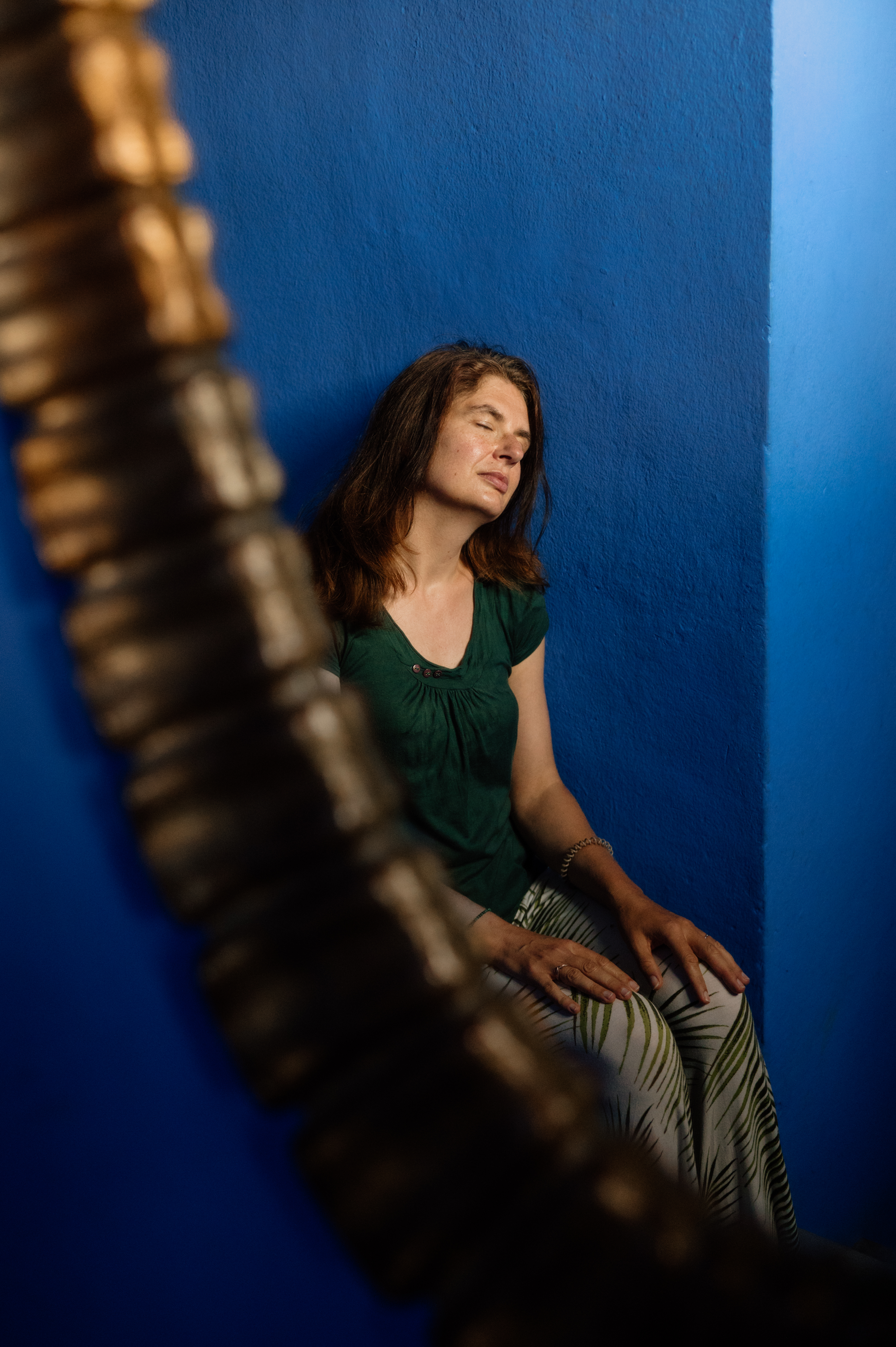 Frau in meditativer Ruhehaltung vor blauer Wand – Blogartikel Yin Yoga und Seelenfotografie
