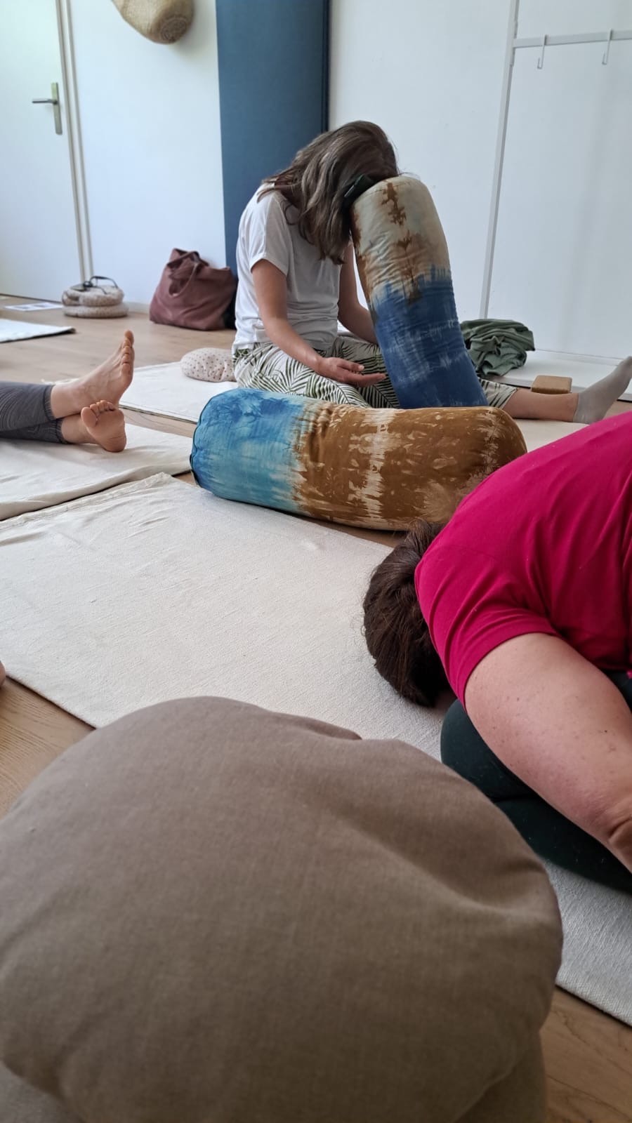 Yin Yoga Gruppe im Studio – Frauen in ruhigen Yogahaltungen auf Matten mit Bolstern, innere Stille